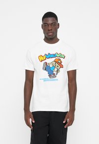 White cotton t-shirt featuring a colorful cartoon graphic. Short sleeves, crew neck, casual fit. Text includes "HUF Worldwide" and care instructions.