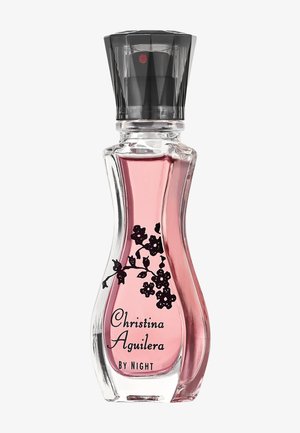 Bottiglia di profumo in vetro curvo con liquido rosa, motivo floreale nero e scritta "Christina Aguilera by Night", con tappo spray nero.