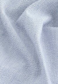 Helle blaue Stoffoberfläche mit einer strukturierten Oberfläche, die ein dezentes Muster aus kleinen, unregelmäßigen Punkten aufweist. Weicher und leicht zerknitterter Erscheinungsbild.