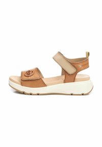 Sandalias de cuero marrón claro con una correa texturizada, velcro ajustable, un acento floral y una suela blanca acolchada. Vista lateral, con un diseño de punta redondeada.