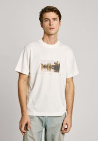 Balta kokvilnas t-kreklu ar kvadrātveida grafiku, uz kuras attēlots upes skats, zem tā izdrukāts zīmola nosaukums "Pepe Jeans", brīvs piegriezums, īsas piedurknes.