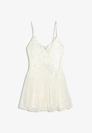 Robe blanche sans manches avec fines bretelles, un petit nœud à l’avant et des ornements en sequins scintillants sur tout le tissu.