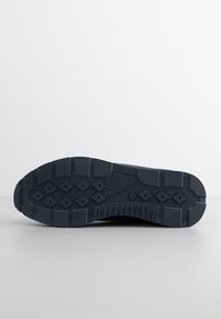 Mörkblå gummisula med texturerat grepp, som har ett diamantmönster och upphöjda rektangulära sektioner för bättre fäste.