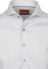 Witte blouse met patroon en een spread collar, voorzien van grijze accenten, met twee knopen zichtbaar op de sluiting. Geverfde stof.