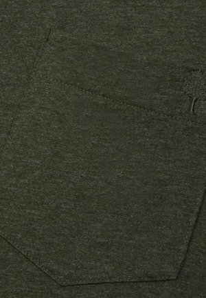 Olivgrüner strukturierter Stoff mit einer sichtbaren Tasche, die genähte Kanten aufweist und ein kleines Baum-Logo in der oberen linken Ecke der Tasche trägt.