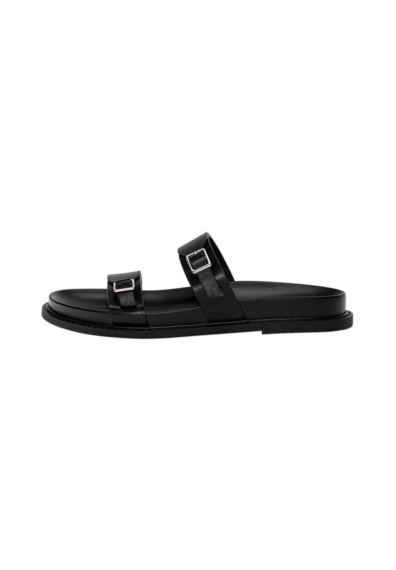 Sandale en cuir noir avec un design minimaliste, comportant deux brides réglables avec boucles métalliques, une semelle plate et une texture lisse.