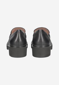 Scarpe slip-on in pelle nera con punta rotonda, suola piatta bassa, texture liscia e dettagli di cucitura minimi.