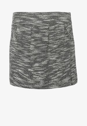 Zwarte blazer over een wit topje, gecombineerd met een gestructureerde grijze rok, zwarte panty en open teen zwarte hakken met gestepte accenten.