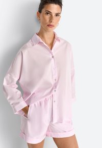 Chemise à boutons en coton rose clair à manches longues, assortie à un short avec taille élastique et poignets.