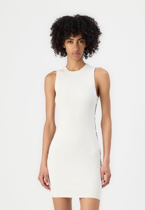 White ribbed sleeveless dress with a fitted silhouette, featuring a side accent of contrasting black detailing along the seam.