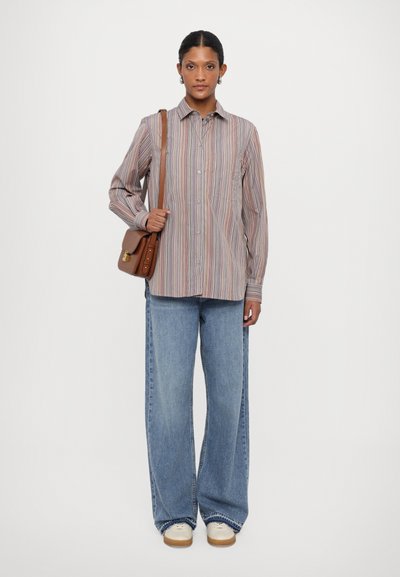 Gestreiftes Hemd in Pastellfarben, kombiniert mit weit geschnittenen blauen Jeans. Die Accessoires umfassen eine braune Umhängetasche und weiße Sneakers.