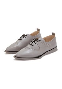 Chaussures en cuir gris clair avec un bout pointu, des lacets noirs, des accents perforés et une semelle compensée basse. Texture lisse avec un design minimal.