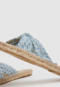 Sandales à enfiler avec semelles en jute tressé et brides en tissu bleu décorées d'un motif abstrait bleu clair.