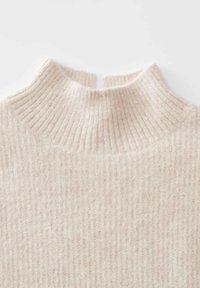 Pull en tricot côtelé de couleur crème douce, avec un col montant court et une petite fente au centre à l'arrière.