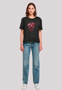 Black cotton t-shirt with a tree graphic made of red and pink hearts; relaxed fit, short sleeves, crew neckline, paired with light blue jeans.