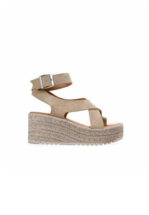 Sandalia cuña de ante beige con plataforma de cuerda trenzada, puntera abierta, tiras cruzadas y correa ajustable en el tobillo con hebilla plateada.