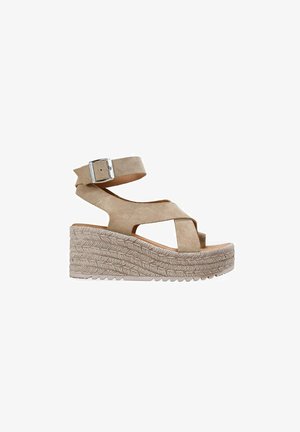 Sandalia cuña de ante beige con plataforma de cuerda trenzada, puntera abierta, tiras cruzadas y correa ajustable en el tobillo con hebilla plateada.