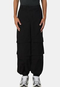 Sorte cargo bukser med en løs pasform, flere frontlommer og lagdelt design. Stoffet synes at være holdbart med en glat tekstur.