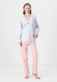 Blusa a rayas azul claro y blanca con cuello grande y redondeado; combinada con pantalones rectos rosa claro. Textura clara; ajuste casual.