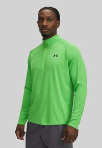 Felgroen langemouwen shirt met een halve rits kraag, gemaakt van gestructureerde stof, met een klein zwart logo op de linkerborst.