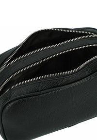 Borsa cosmetica in pelle nera con tre scomparti con cerniera. Superficie testurizzata e accessori in metallo argentato per le cerniere. Interno foderato.