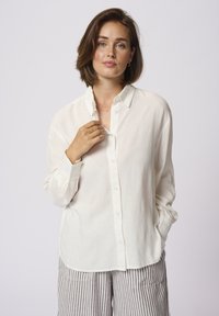 Ivoor kraaghemd van lichtgewicht stof met lange mouwen, knoopsluiting aan de voorkant en geplooide manchetten, casual gestyled met gestreepte broek.