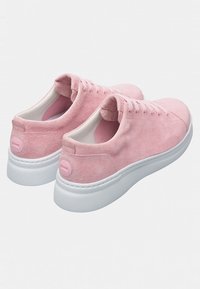 Pink suede sneakers with white rubber soles, featuring a smooth texture, rounded shape, and subtle branding on the heel.