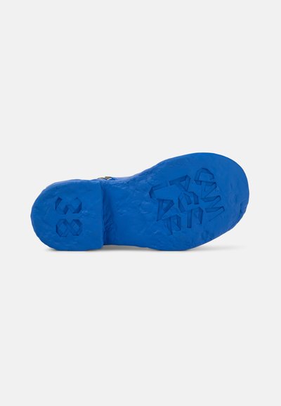 Sole in gomma blu con presa testurizzata, caratterizzata da motivi geometrici in rilievo e numeri. Design spesso e scolpito che aggiunge interesse visivo.