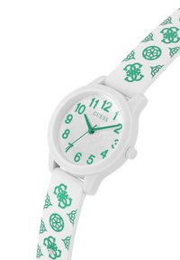 Vit rund klocka med en grön urtavla, arabiska siffror och gröna visare. Armbandet har upprepade gröna mönster och logotypaccenter.