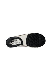 Suola di scarpa sportive marrone e bianca con un fondo in gomma nera texturizzata. Presenta il logo "THE NORTH FACE" in bianco. Motivo a rientranza triangolare.