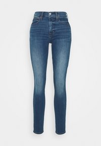 Jeans ajustados de denim azul oscuro, con una cintura alta, un ligero desgastado y un diseño clásico de cinco bolsillos con detalles en metal plateado.