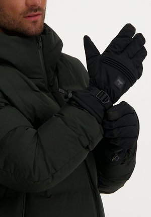 Black insulated gloves with textured palm and elastic wrist straps, worn by a person in a green puffer jacket.