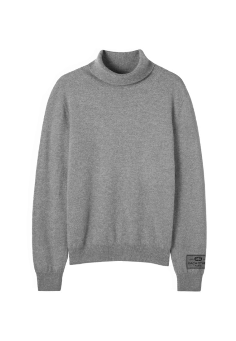 Szary sweter typu golf wykona z miękkiego materiału o dzianinowej strukturze. Posiada długie rękawy i prążkowane mankiety, z metką na dolnym lewym rogu.