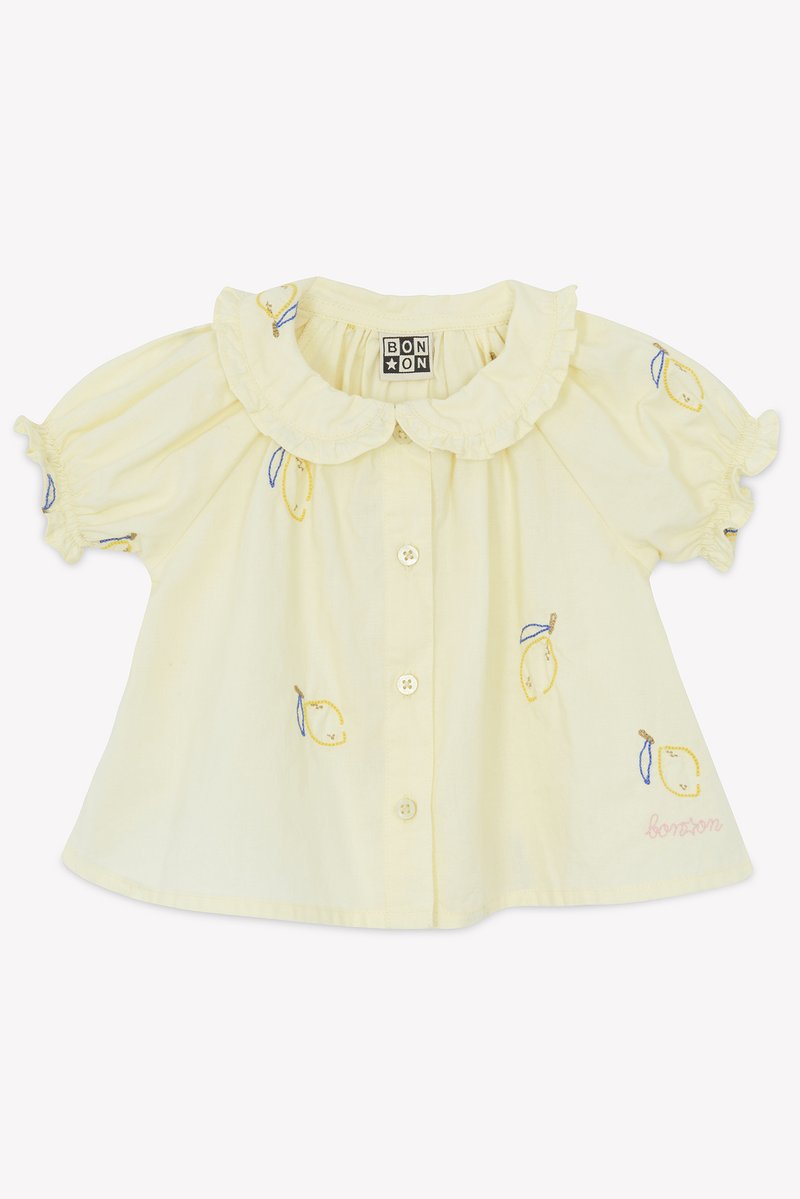 Yellow blouse with short puff sleeves, ruffled collar, fruit embroidery, and button closure. Features brand name stitched in pink.