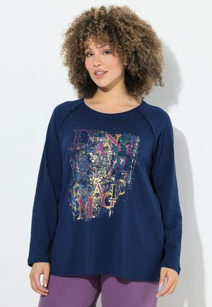 Chemise à manches longues bleu marine avec un col arrondi, affichant un imprimé graphique multicolore indiquant "DANCE MAGIC" en lettres grasses.