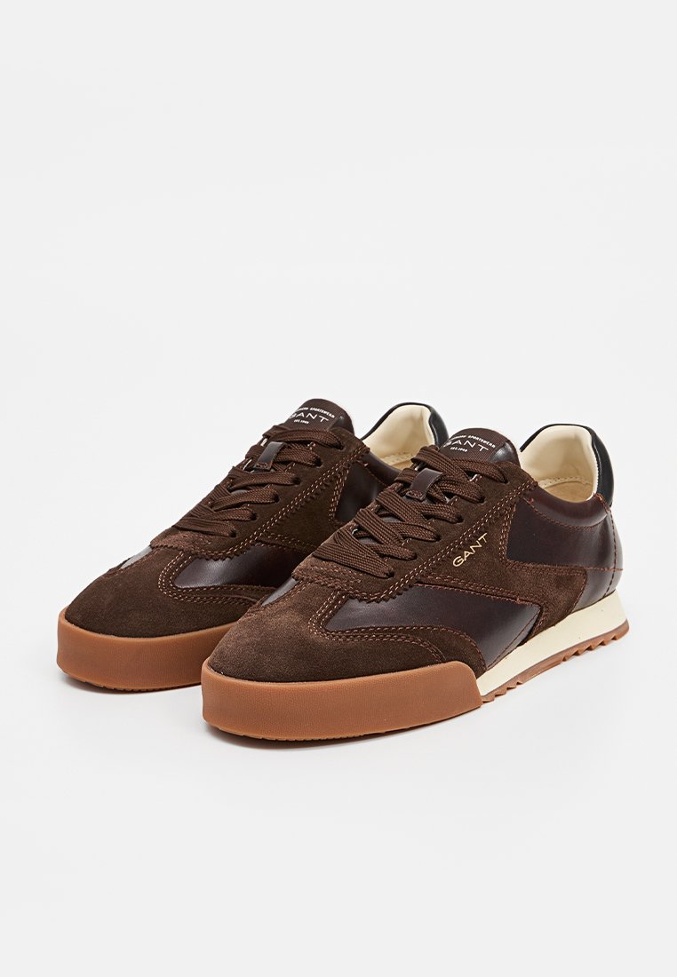 Braune Wildleder- und Ledersneaker mit Gummisohle, ausgestattet mit einem Schnürdesign, kontrastierenden Akzenten und einem Logo auf der Zunge.