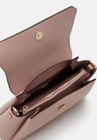 Roze leren handtas met een gouden druksluiting, voorzien van een binnenzak met ritssluiting en open compartimenten. Gladde textuur met donkere randaccenten.