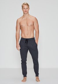 Dunkelgraue Jogginghosen aus weichem, atmungsaktivem Stoff mit einem Kordelzugbund und schmal zulaufenden Beinen. Keine sichtbaren Muster oder Verzierungen.