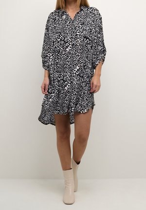 Schwarz-weißes Animal-Print-Kleid mit Kragen, lockerem Schnitt, dreiviertel Ärmeln und gebogenem Saum. Glatte Stoffstruktur.