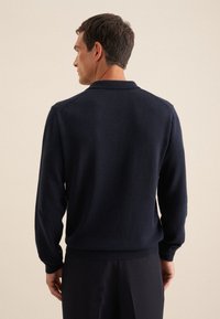 Marineblaue Strickjacke mit Kragen und geripptem Saum. Sie hat lange Ärmel und eine glatte Textur, gezeigt von hinten.