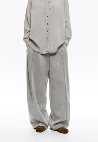 Gray denim shirt with a button placket paired with wide-leg gray denim pants. Soft texture, large pockets, and subtle contrast stitching.