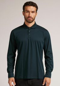 Langarm-Poloshirt in Dunkelgrün, aus glattem Stoff gefertigt, mit klassischem Kragen und drei Knöpfen. Einfaches Design, keine Muster.