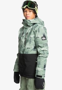 Zielono-czarna kurtka narciarska z abstrakcyjnymi wzorami. Posiada wysoki kołnierz, kieszenie na zamek oraz naszywkę z logo na rękawie.