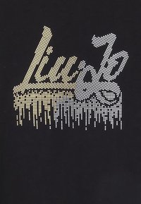 Czarna koszulka z designerskim napisem z kryształków w gradientowych odcieniach złota i bieli, z efektem kapiącym na dole.