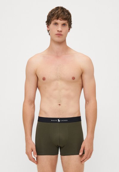 Boxers de cor verde-azeitona feitos de algodão, com uma banda elástica preta com marcação branca. Textura suave e design ajustado.