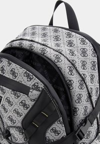 Zaino nero e grigio con motivo trapuntato, dotato di un logo, maniglia superiore, spallacci regolabili e scomparto principale con zip.