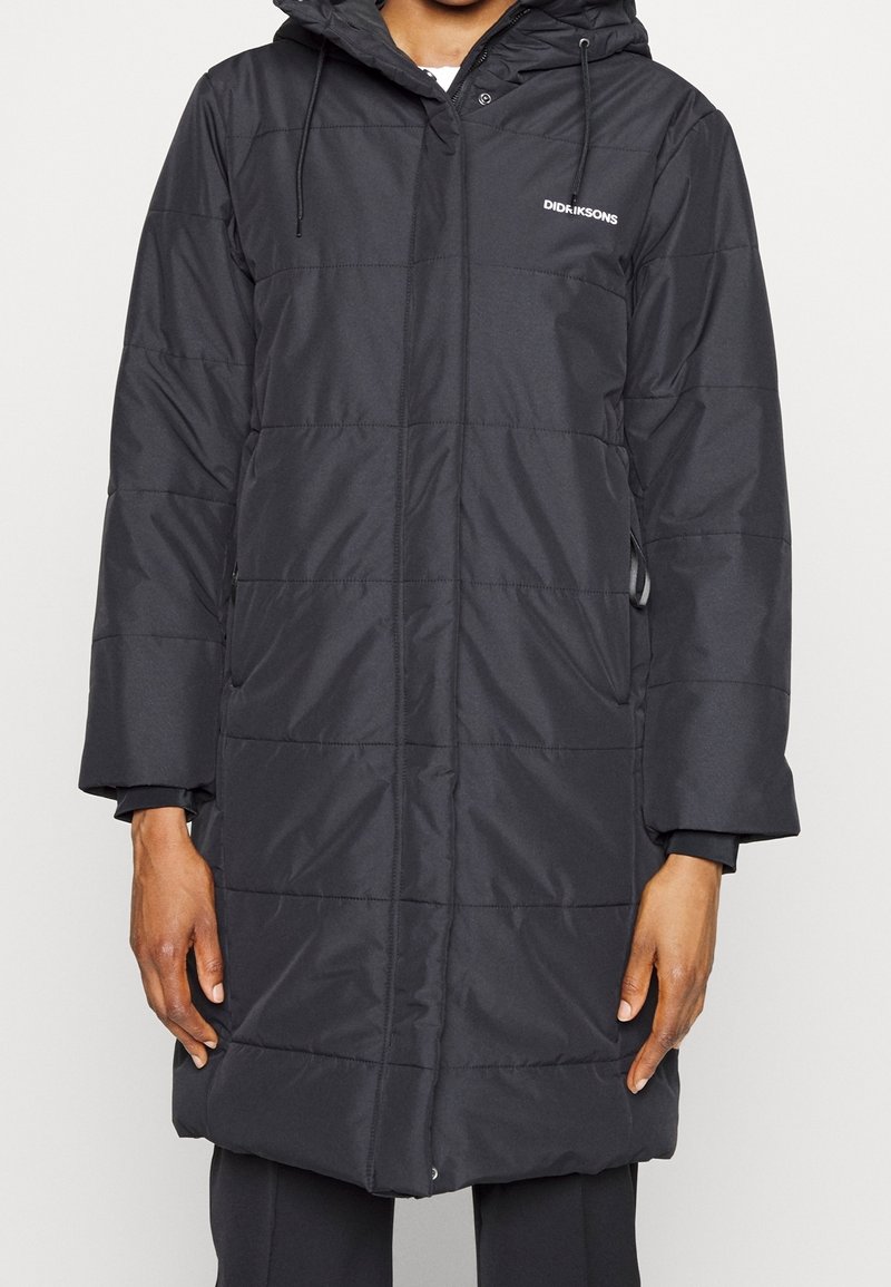 Manteau matelassé noir avec capuche, fabriqué en matériau résistant à l'eau, avec fermeture éclair à l'avant et poches latérales. Logo de la marque sur le coin supérieur gauche.