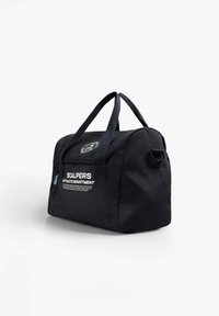 Bolsa de viaje de tela negra con asas dobles, forma redondeada, logo frontal en texto blanco y detalle de bolsillo con cremallera lateral.