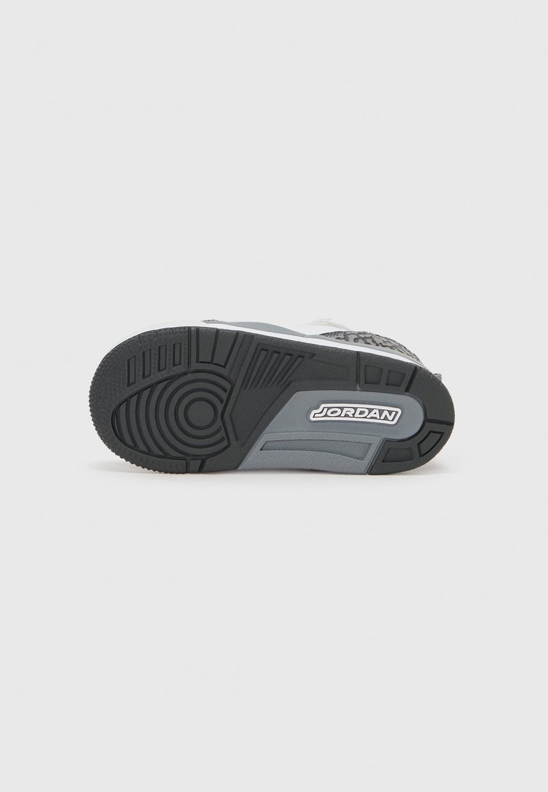 Zwart-witte sneakersole met gestructureerd rubber, cirkelvormig loopvlakpatroon, gladde accenten en een witte 'JORDAN'-logo aan de zijkant.