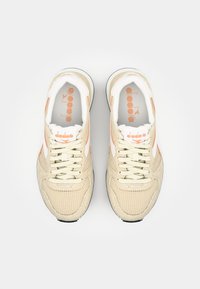 Beige athletic shoes featuring mesh and suede materials, white and orange accents, round toe, and lace-up closure.